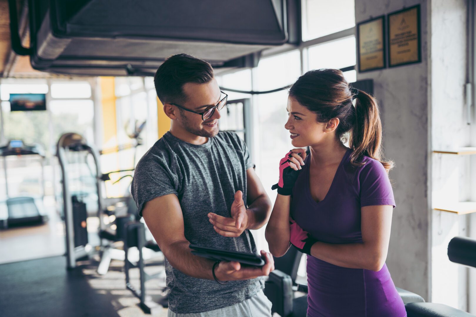 Trainer showing workout plan to smiling gym client