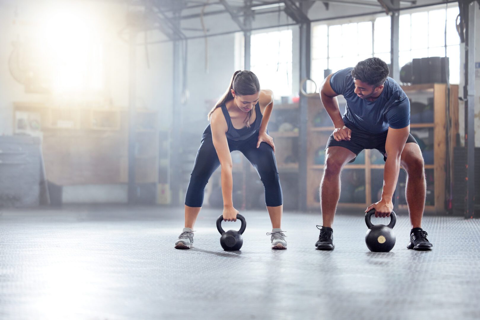 Two people doing kettlebell workout in gym
