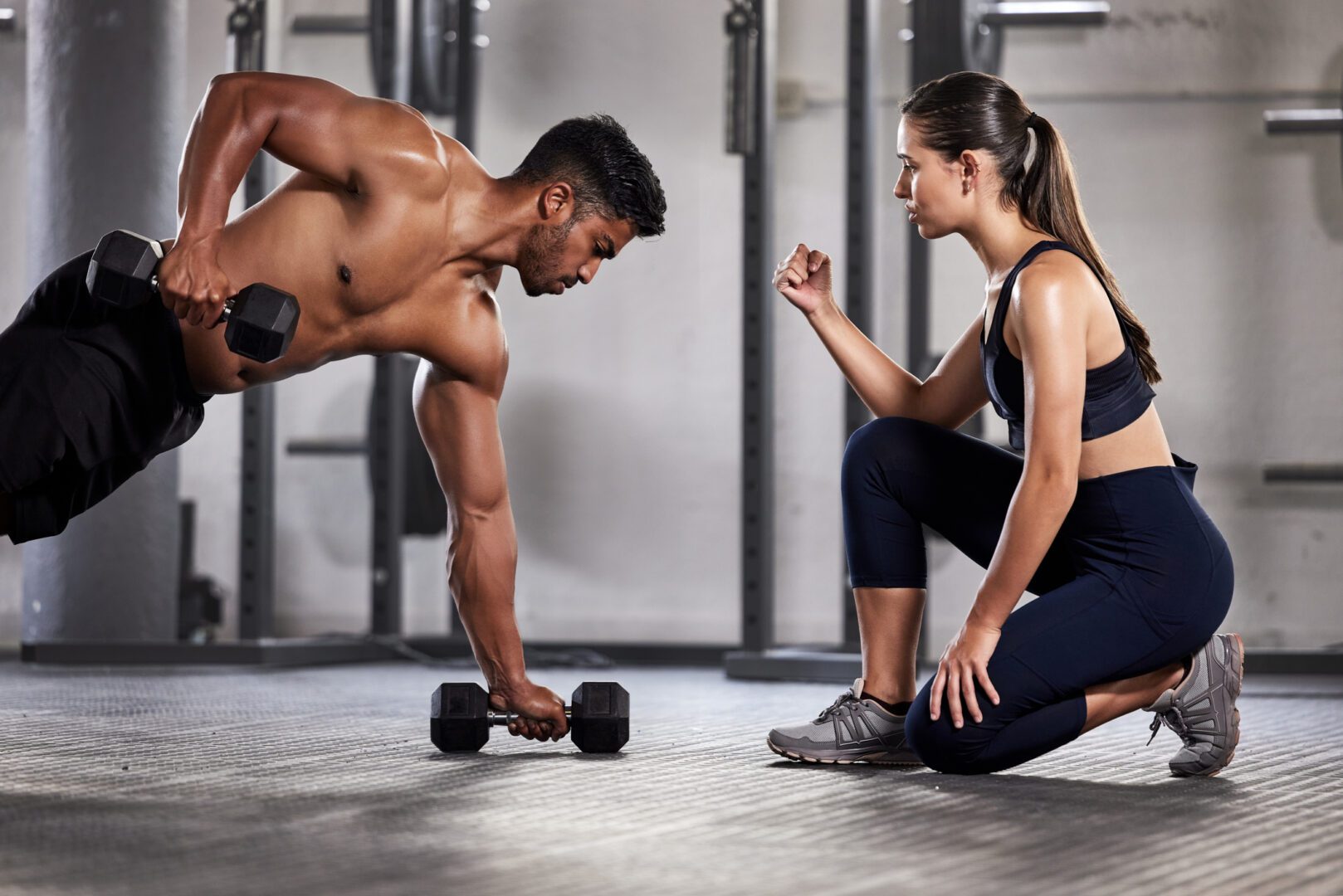 Trainer coaching man performing dumbbell row