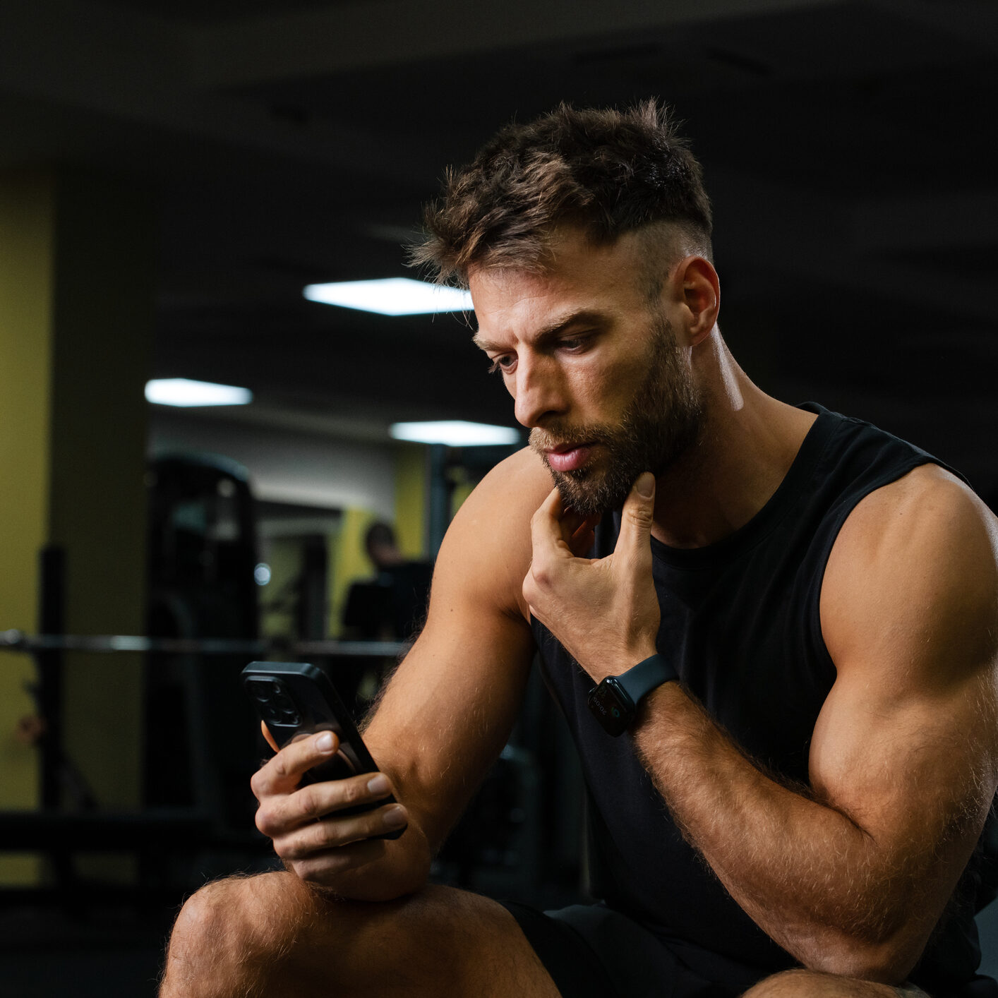 Muscular man checking phone in gym