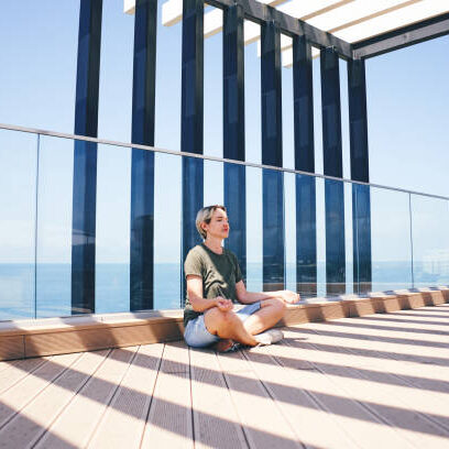 Woman meditating on a sunlit terrace.